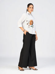 Stylish women’s white shirt with floral embroidery and black contrast collar showcased in studio lighting.