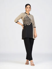 Woman wearing a dual-tone beige and black kurti with a bold embroidered leaf appliqué in front.