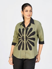 Front view of a model showcasing a stylish olive green button-down top with bold black print and matching wide-leg pants.