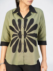 Fashion model posing in a modern olive and black co-ord outfit featuring floral-style prints and flared bottoms.