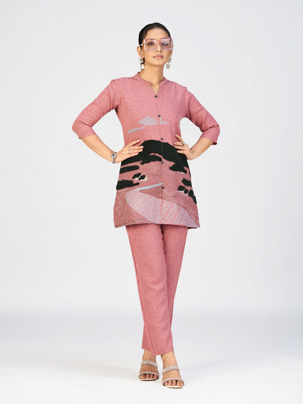 Close-up view of a woman wearing a pink textured kurti with scenic embroidery and button-down front.