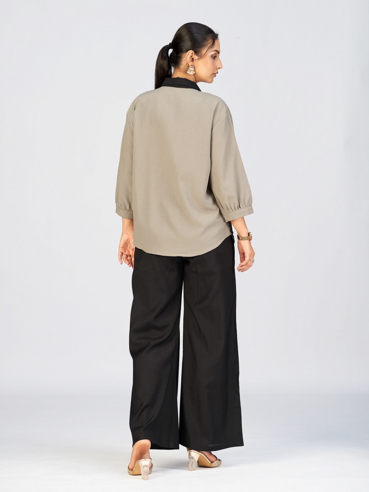 Front view of a model in a beige button-down top featuring intricate black leaf embroidery.