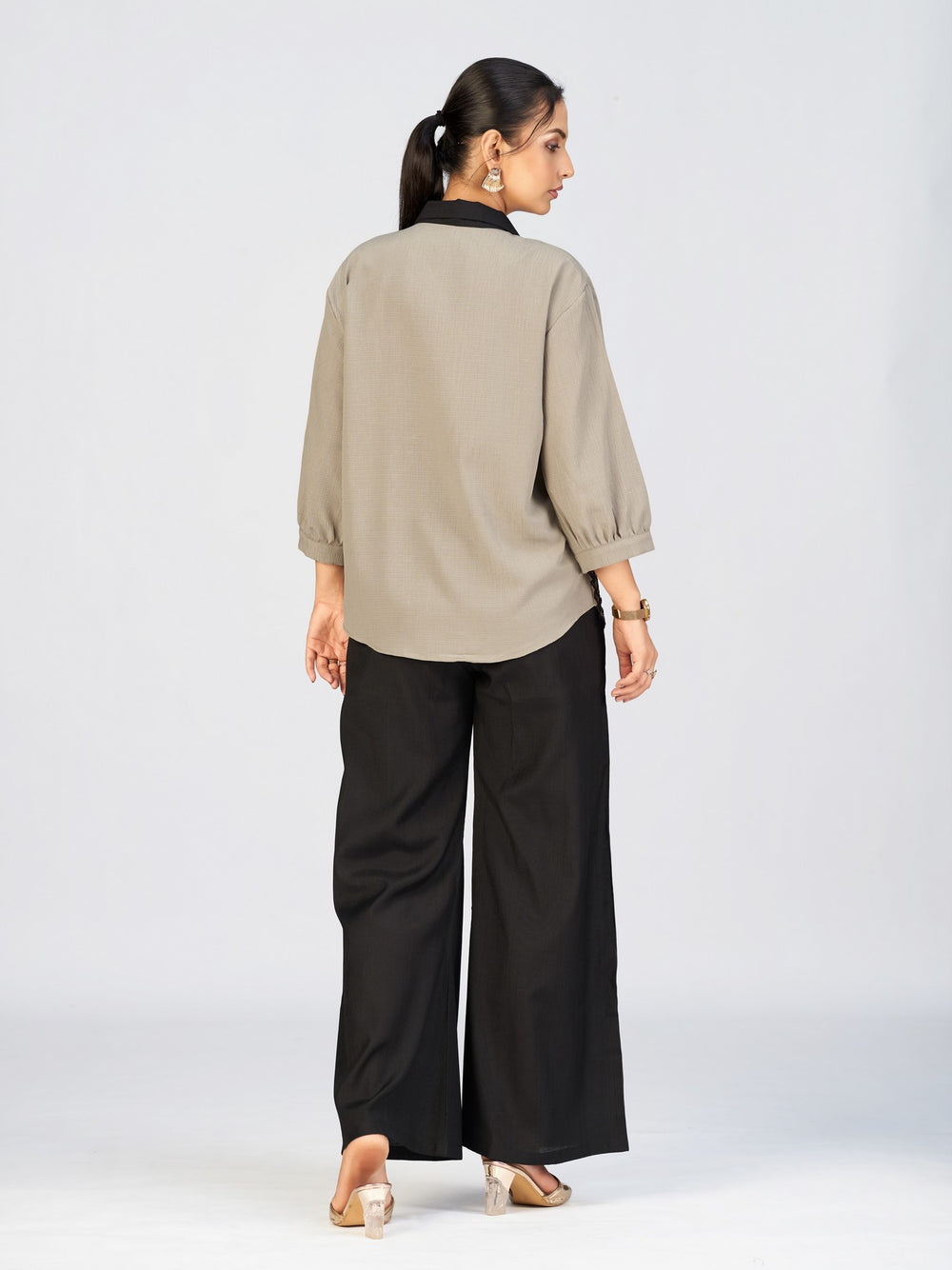 Front view of a model in a beige button-down top featuring intricate black leaf embroidery.