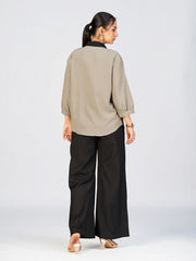 Front view of a model in a beige button-down top featuring intricate black leaf embroidery.