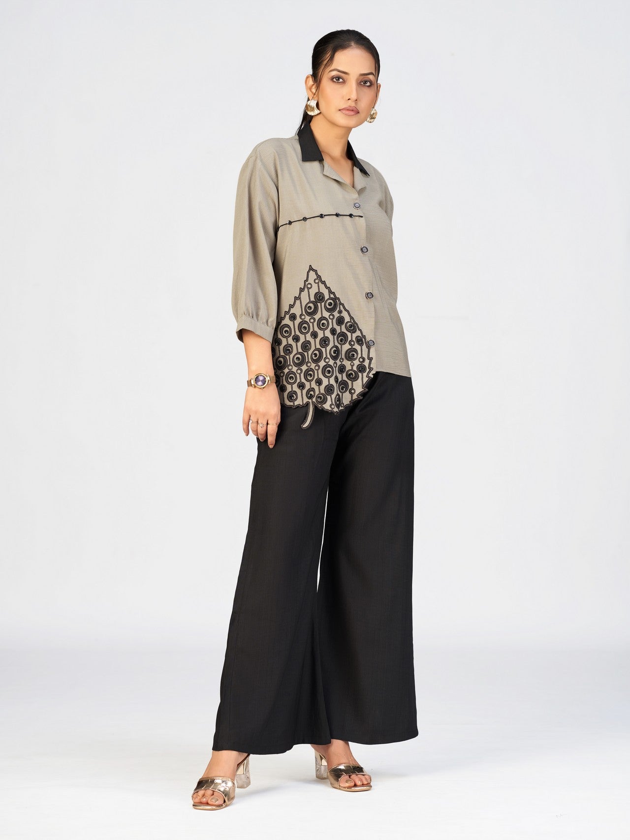 Stylish women’s beige shirt with black collar and decorative applique near the hem.