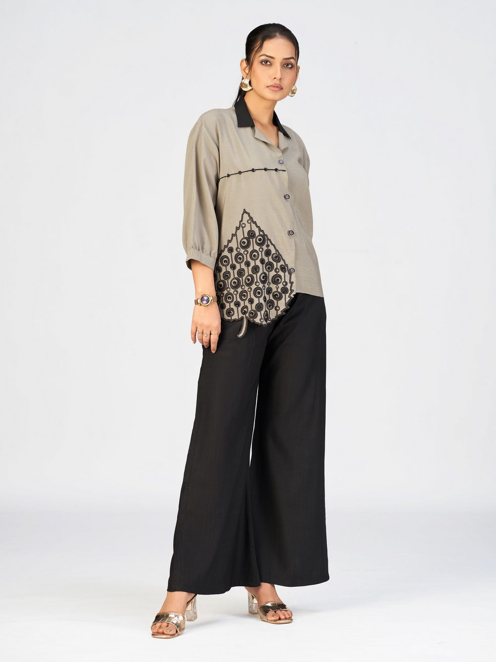 Stylish women’s beige shirt with black collar and decorative applique near the hem.