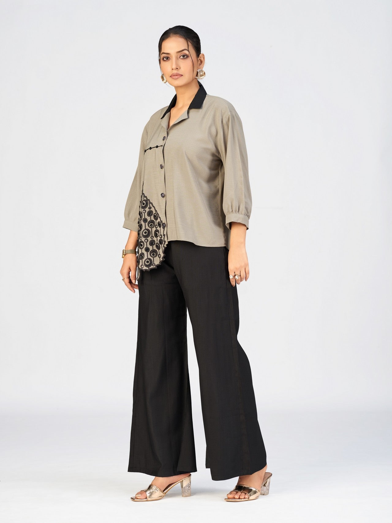 Close-up of beige embroidered shirt showing detailed black applique work.