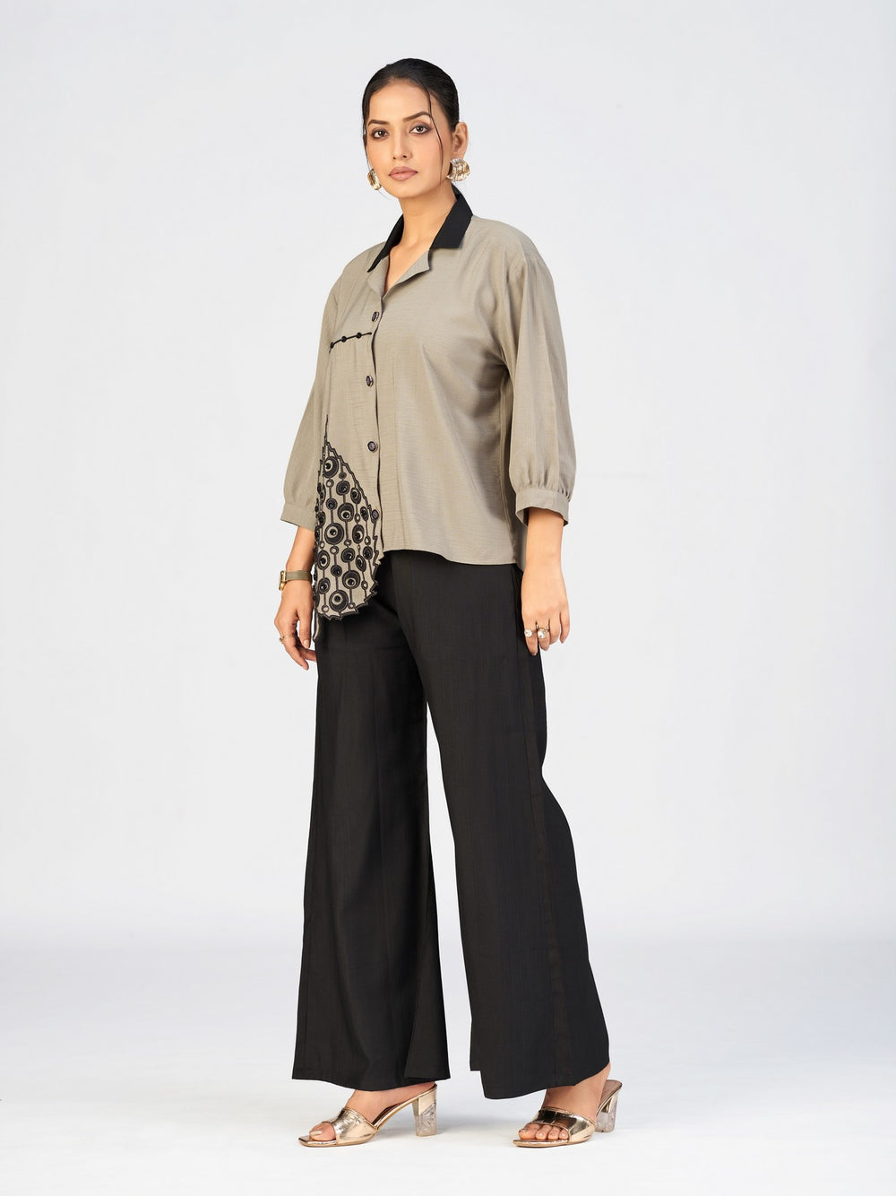 Close-up of beige embroidered shirt showing detailed black applique work.