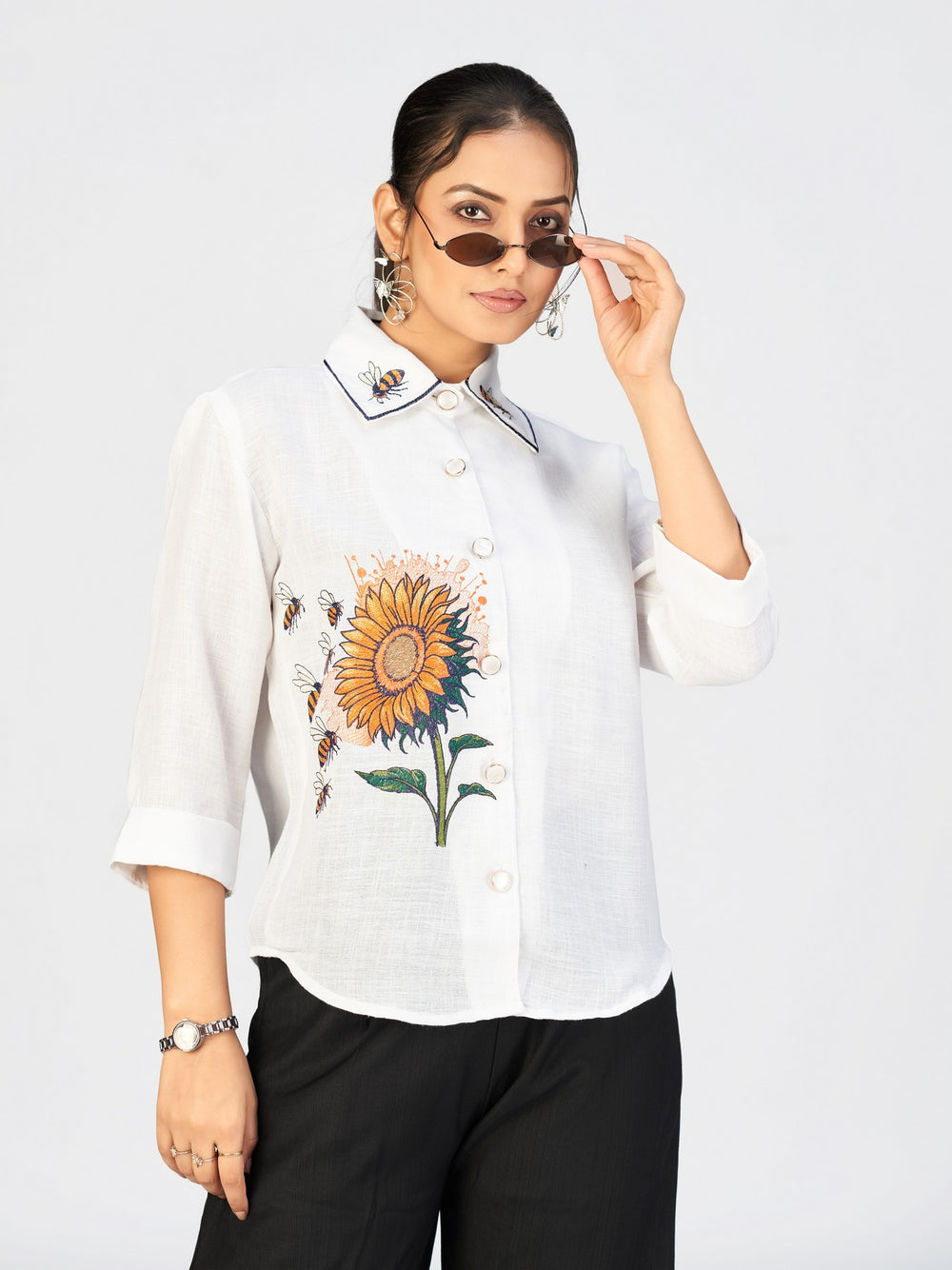 Elegant embroidered sunflower design on a white casual shirt worn by a woman.