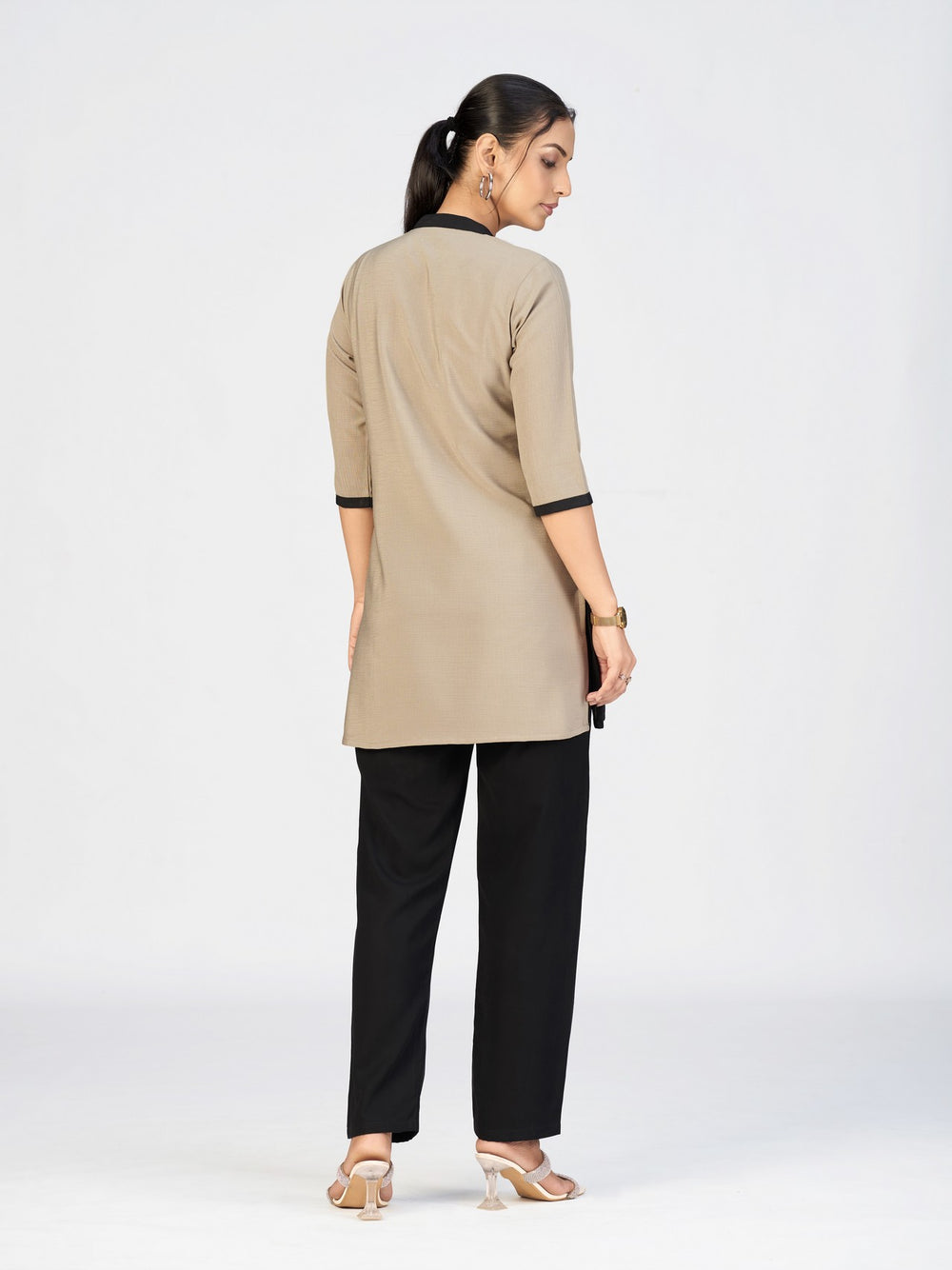 Front view of a model dressed in a beige and black kurti featuring artistic leaf embroidery.