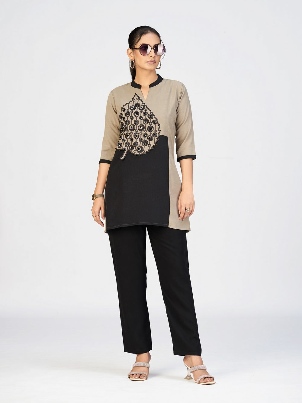 Elegant beige and black kurti with embroidered detailing showcased in a studio setting.