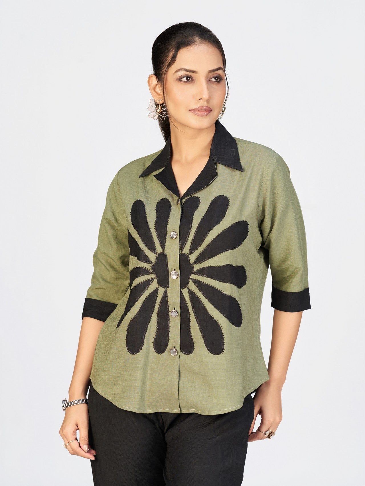 Front view of a model showcasing a stylish olive green button-down top with bold black print and matching wide-leg pants.