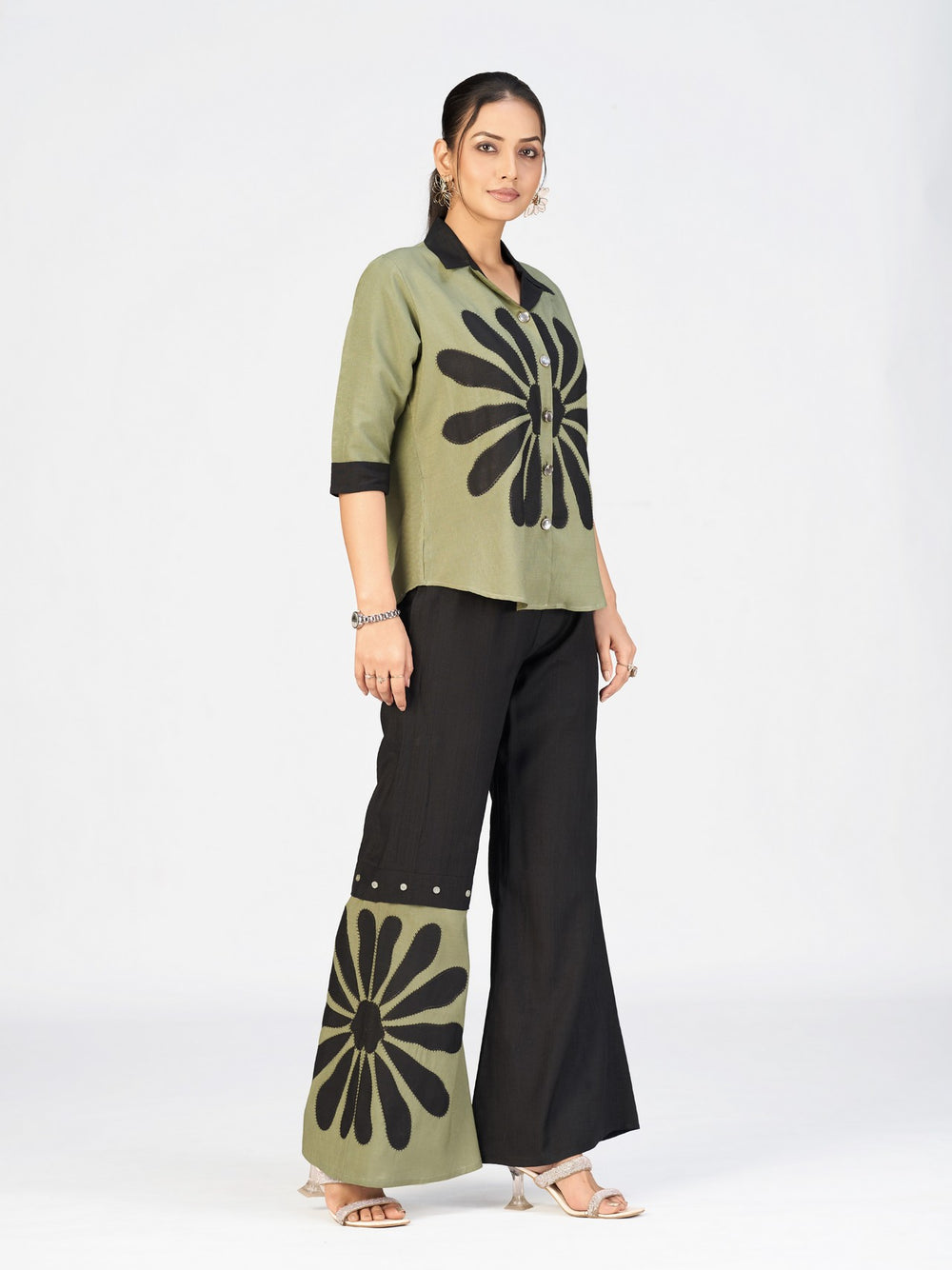 Elegant women’s two-piece outfit with a printed green shirt and black flared pants displayed by a model.