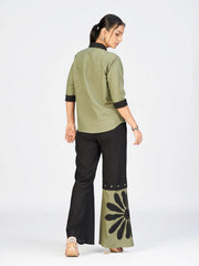 Model standing in a chic printed co-ord ensemble with buttoned shirt and contrast wide-leg pants.