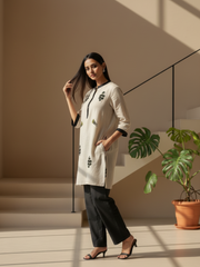 Female model showcasing a simple beige kurti with subtle embroidery and three-quarter sleeves.