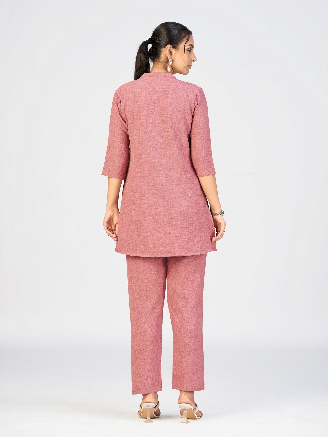 Pink embroidered kurti featuring sun and cloud motifs styled by a female model.