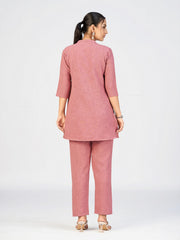 Pink embroidered kurti featuring sun and cloud motifs styled by a female model.