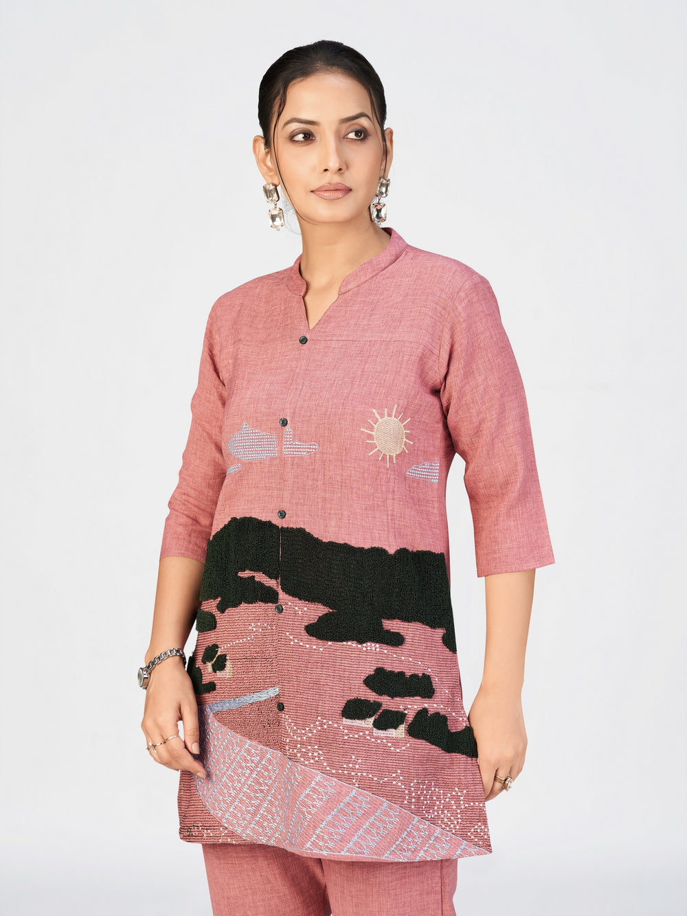 Detailed shot of a women’s kurti with intricate black landscape embroidery on a pink fabric base.
